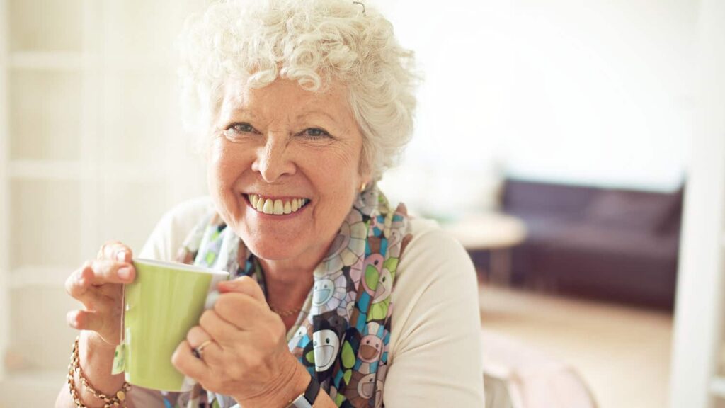 old lady smiling while holding a cup